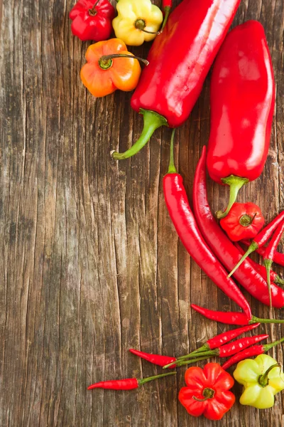 Kolorowe papryki słodkiej i hot chili peppers na drewniane tła — Zdjęcie stockowe