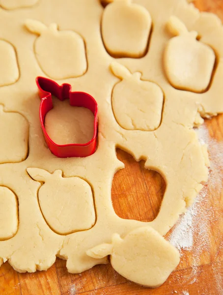 Elma şeklinde çerez kesici pişmemiş kurabiye hamuru üzerine — Stok fotoğraf