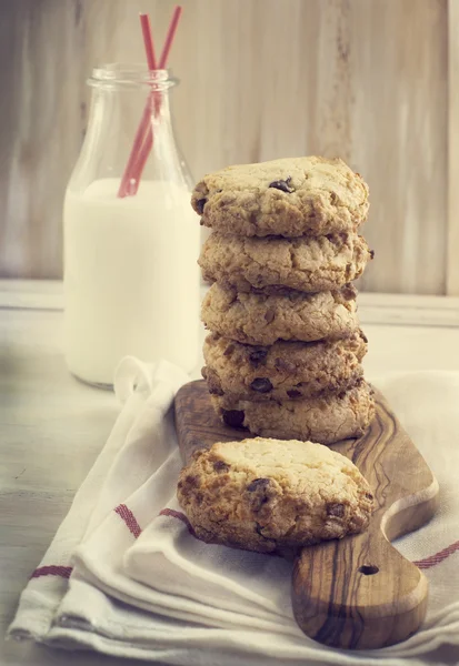 Biscotti al cioccolato sul piano di cottura e bottiglia di latte . — Foto Stock