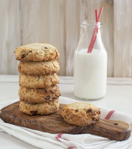 Biscuits aux pépites de chocolat sur plaque de cuisson et bouteille de lait . — Photo