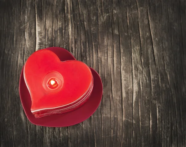 Červený hořící srdce ve tvaru svíčky na dřevěné pozadí. — Stock fotografie