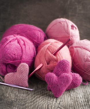 Crochet pink hearts and yarn on wooden background clipart