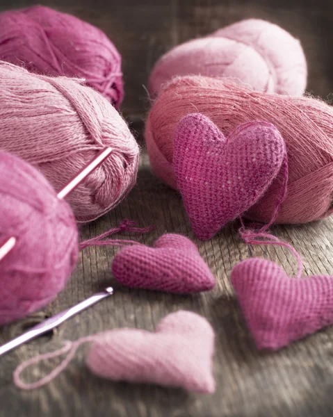 Crochet pink hearts and yarn on wooden background. Selective fo — Stock Photo, Image