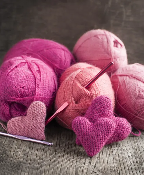 Crochet pink hearts and yarn on wooden background — Stock Photo, Image