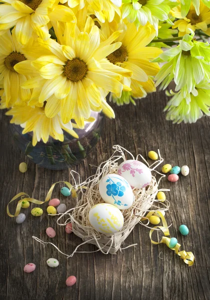 Natureza morta com ovos de Páscoa em cesta e buquê de flores — Fotografia de Stock