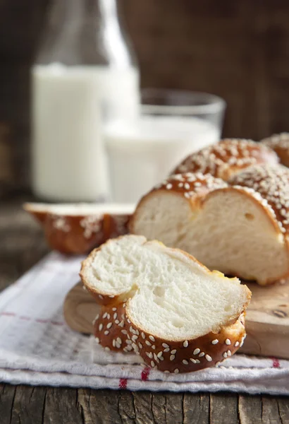 Свежеиспеченный сладкий плетеный хлеб и стакан молока — стоковое фото