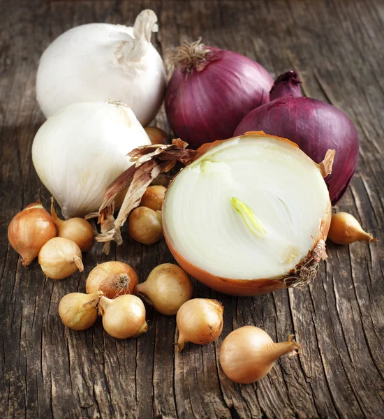 Different varieties of onions on a wooden background — Stock Photo, Image