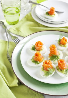 Stuffed eggs. Hard boiled eggs with avocado filling and smoked salmon clipart