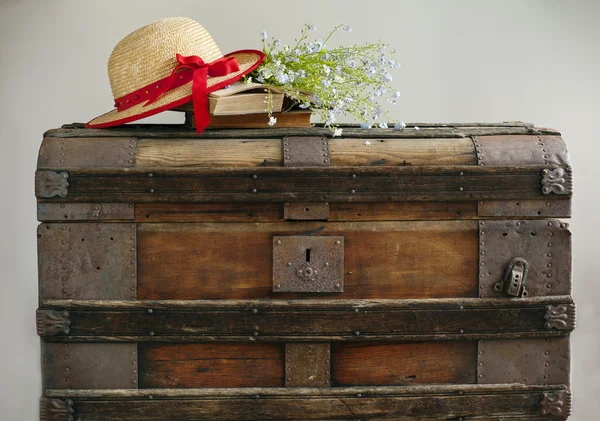 Summer blue flowers, old books and straw hat on old vintage ches