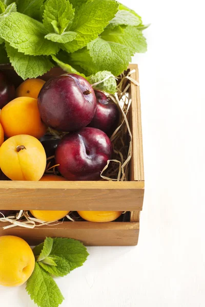Čerstvé meruňky a švestky v dřevěné krabici — Stock fotografie