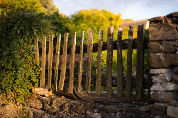 Old wooden picket fence built into a wall from stones.