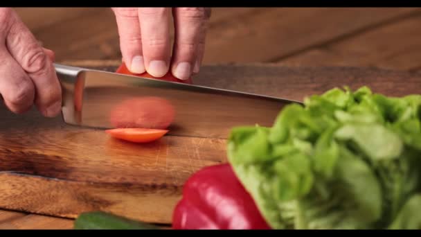 Чоловік руками ріже помідор на обробній дошці — стокове відео