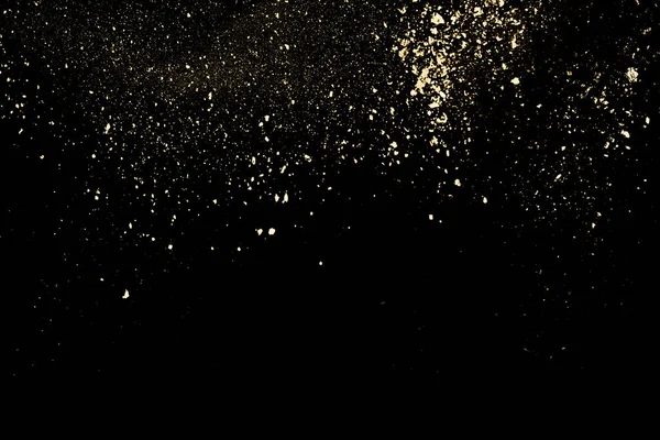 Siyah arka planda altın tozu patlaması. Hareketi dondur.