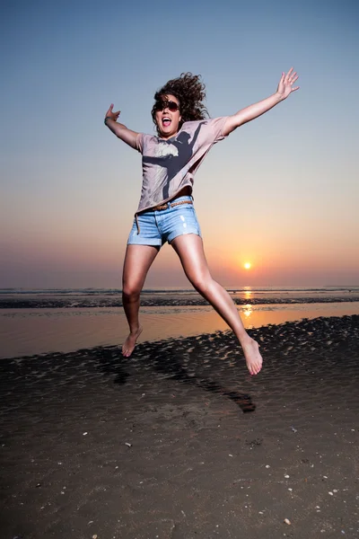 Menina bonita com cabelo castanho se divertindo na praia ao pôr do sol . — Fotografia de Stock