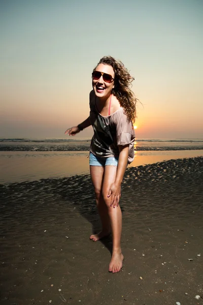 Hübsches Mädchen mit braunen Haaren amüsiert sich am Strand bei Sonnenuntergang. — Stockfoto