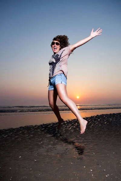 Hübsches Mädchen mit braunen Haaren amüsiert sich am Strand bei Sonnenuntergang. — Stockfoto