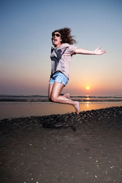 Menina bonita com cabelo castanho se divertindo na praia ao pôr do sol . — Fotografia de Stock