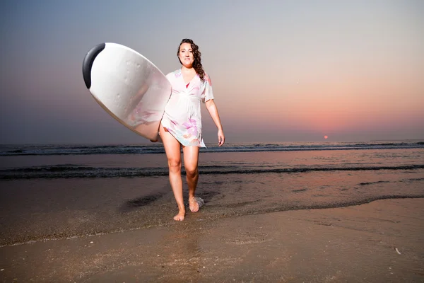 Mooie surf meisje op het strand bij zonsondergang. — Stockfoto