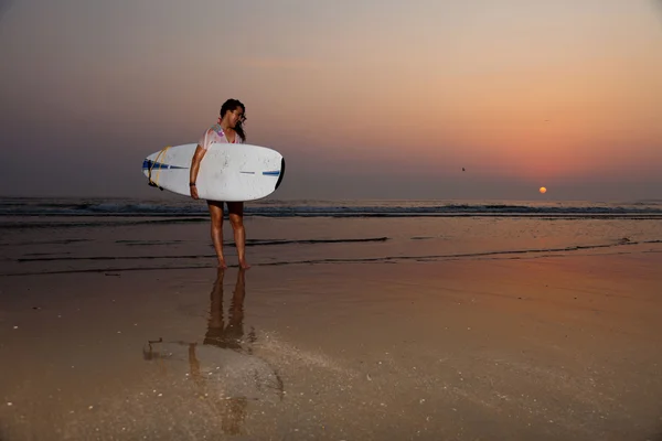 Mooie surf meisje op het strand bij zonsondergang. — Stockfoto