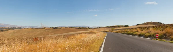 Beautiful panoramic photo of road through Sierra de Grazalema Natural Park. On the road. Blue cloudy sky. Golden fields. Amazing scenery. Andalusia. Spain. — Stock Photo, Image