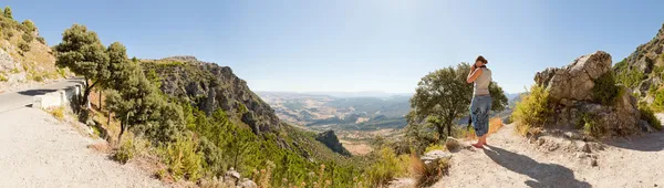 Panoramic landscape photo of Sierra de Grazalema national park. Female tourist taking pictures of the amazing landscape. Beautiful scenery. Blue sky. Malaga. Andalusia. Spain.