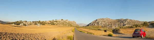 Beautiful panoramic photo of road through the amazing rocky mountain landscape of Sierra de Grazalema Natural Park at sunset. Rocks and pine trees. Blue sky. Andalusia.