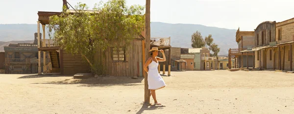 Foto panorâmica de turista feminina morena com chapéu e vestido branco na cidade ocidental Fort Bravo. Texas Hollywood. Desierto de Tabernas, Almeria. Andaluzia. Espanha . — Fotografia de Stock