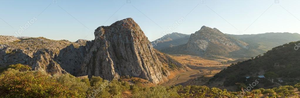 Beautiful panoramic photo of the amazing rocky mountain landscape of Sierra de Grazalema Natural Park at sunset. Rocks and pine trees. Blue sky. Andalusia. Spain.