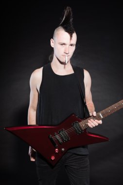 punk rock adam kırmızı elektro gitar ve mohawk saç kesimi. etkileyici bir yüz. siyah arka plan üzerine izole. Stüdyo vurdu.