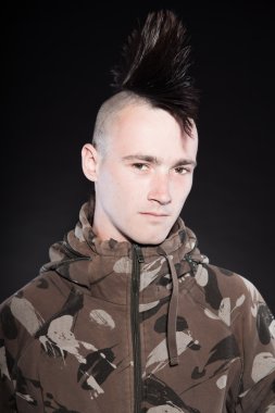 Mohikan saç kesimi olan serseri bir adam. etkileyici bir yüz. Army Kamuflaj ceketi. siyah arka plan üzerine izole. Stüdyo vurdu.