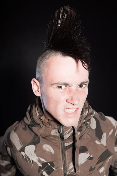 Hombre punk con corte de pelo mohawk. Cara expresiva. Chaqueta camuflaje del ejército. Aislado sobre fondo negro. Captura de estudio . — Foto de Stock