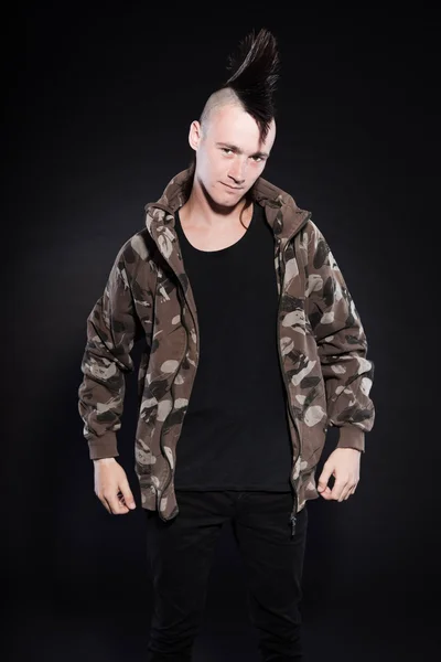 Punk man with mohawk haircut. Expressive face. Army camouflage jacket. Isolated on black background. Studio shot. — Stock Photo, Image