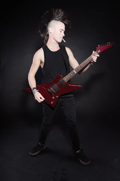 Punk rock férfi piros elektromos gitár és a mohawk hajvágás. kifejező arc. elszigetelt, a fekete háttér. stúdió felvétel. — Stock Fotó