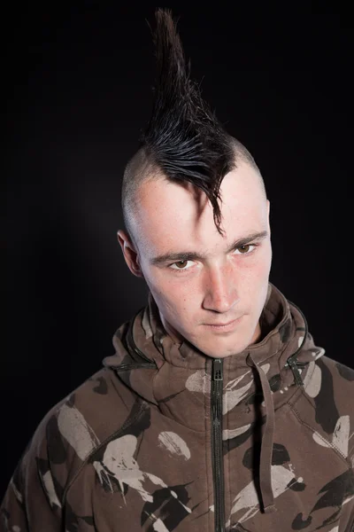 Punk man with mohawk haircut. Expressive face. Army camouflage jacket. Isolated on black background. Studio shot. — Stock Photo, Image