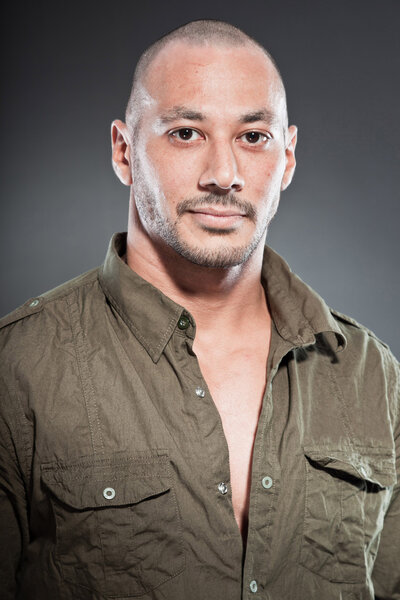 Muscled tough guy wearing green army shirt. Good looking man. Isolated on grey background. Studio shot. Healthy. Fitness.