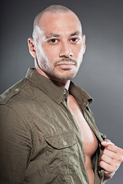 Muscled tough guy wearing green army shirt. Good looking man. Isolated on grey background. Studio shot. Healthy. Fitness.