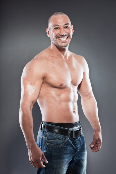 Shirtless muscled fitness man. Cool looking. Tough guy. Brown eyes. Bald. Tanned skin. Studio shot isolated on grey background.