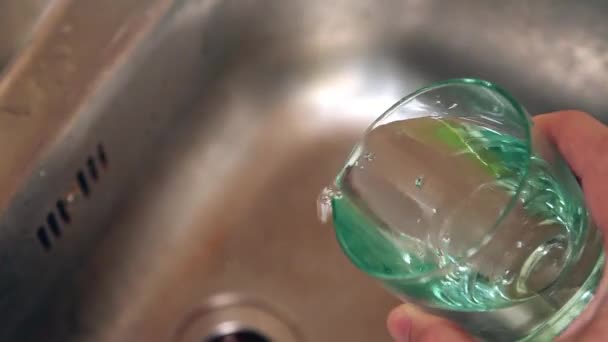 Leeg glas water in de gootsteen. mannenhand bedrijf glas. — Stockvideo