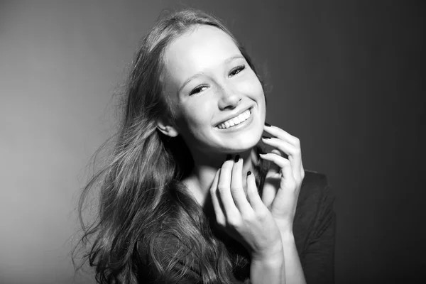 Glada leende ganska ung tjej med långt blont hår. svarta och vita studio porträtt. mode skönhet stil. isolerad på grå bakgrund. — Stockfoto