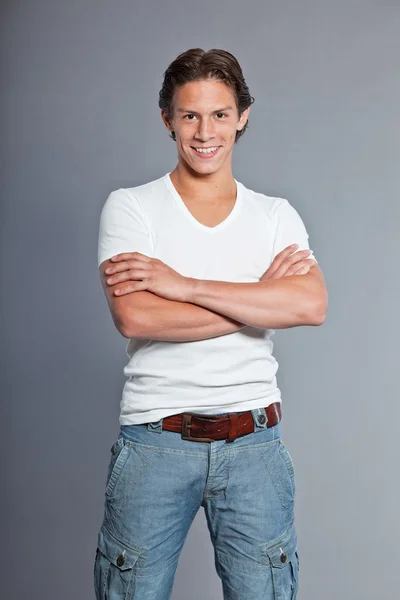 Adolescente com cabelo castanho e olhos. Vestindo camiseta branca e calções azuis. Boa aparência. Vestuário casual. Expressões. Retrato de estúdio isolado sobre fundo cinza . — Fotografia de Stock