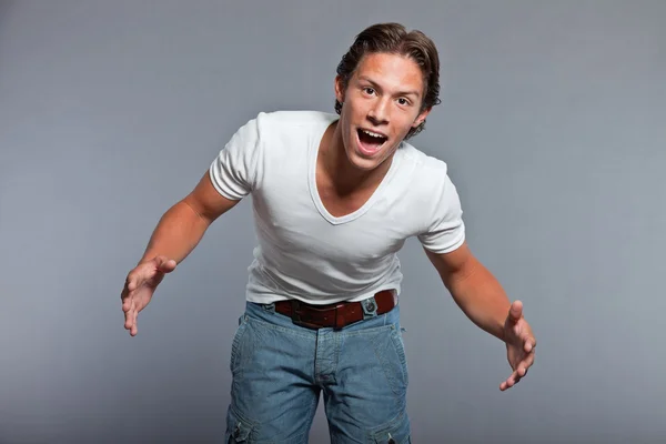 Teenage boy with brown hair and eyes. Wearing white t-shirt and blue shorts. Good looking. Casual wear. Expressions. Studio portrait isolated on grey background. — Stock Photo, Image