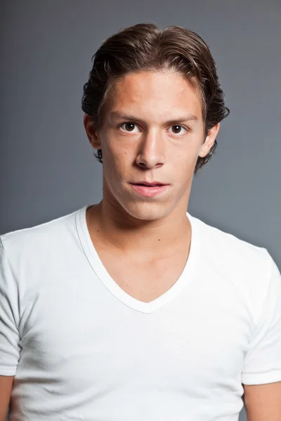 Tiener met de ogen en bruin haar. het dragen van witte t-shirt. Knap. vrijetijdskleding. expressies. Studio close-up portret geïsoleerd op grijze achtergrond. — Stockfoto