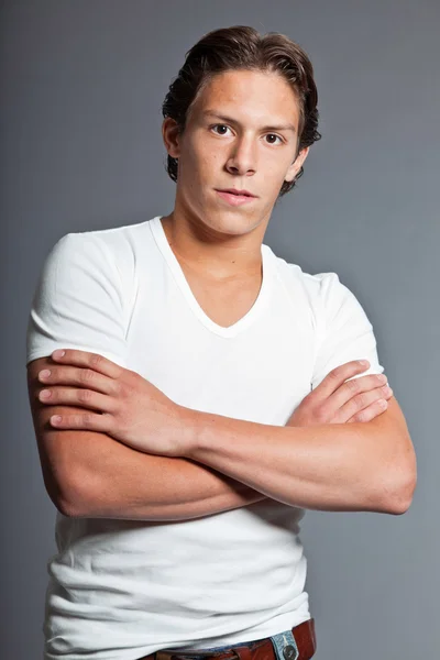 Teenage boy with brown hair and eyes. Wearing white t-shirt. Good looking. Casual wear. Expressions. Studio closeup portrait isolated on grey background. — Stock Photo, Image