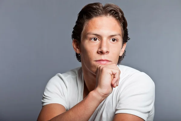 Adolescente con cabello castaño y ojos. Llevando una camiseta blanca. Muy guapo. Ropa casual. Expresiones. Estudio primer plano retrato aislado sobre fondo gris . — Foto de Stock