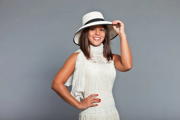 Pretty girl with brown hair and skin wearing white dress and hat. Expression. Good looking. Chique wear. Studio portrait isolated on grey background. — Stock Photo, Image