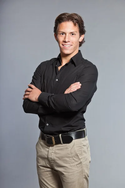 Adolescente con cabello castaño y ojos. Con camisa negra y pantalones caqui. Muy guapo. Ropa casual. Expresiones. Retrato de estudio aislado sobre fondo gris . —  Fotos de Stock