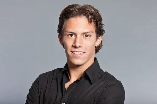 Ragazzo con i capelli castani e gli occhi. Indossava camicia nera e pantaloni kaki. Bell'aspetto. Abbigliamento casual. Espressioni. Studio ritratto isolato su sfondo grigio . — Foto Stock