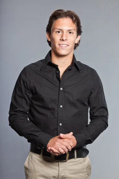 Adolescente con cabello castaño y ojos. Con camisa negra y pantalones caqui. Muy guapo. Ropa casual. Expresiones. Retrato de estudio aislado sobre fondo gris . — Foto de Stock