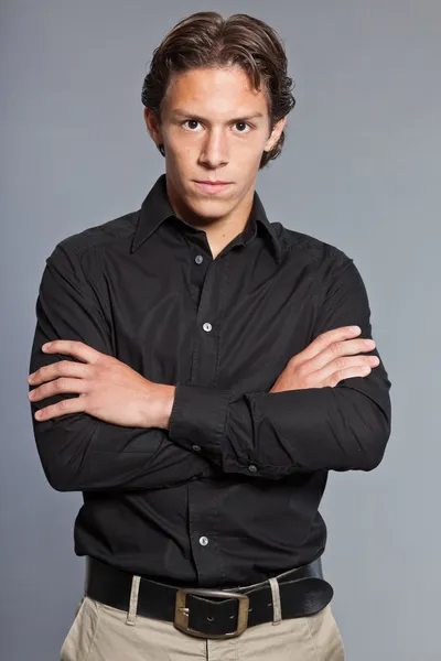 Adolescente con cabello castaño y ojos. Con camisa negra y pantalones caki. Muy guapo. Ropa casual. Expresiones. Retrato de estudio aislado sobre fondo gris . —  Fotos de Stock