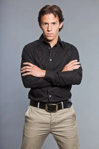 Adolescente con cabello castaño y ojos. Con camisa negra y pantalones caki. Muy guapo. Ropa casual. Expresiones. Retrato de estudio aislado sobre fondo gris . —  Fotos de Stock